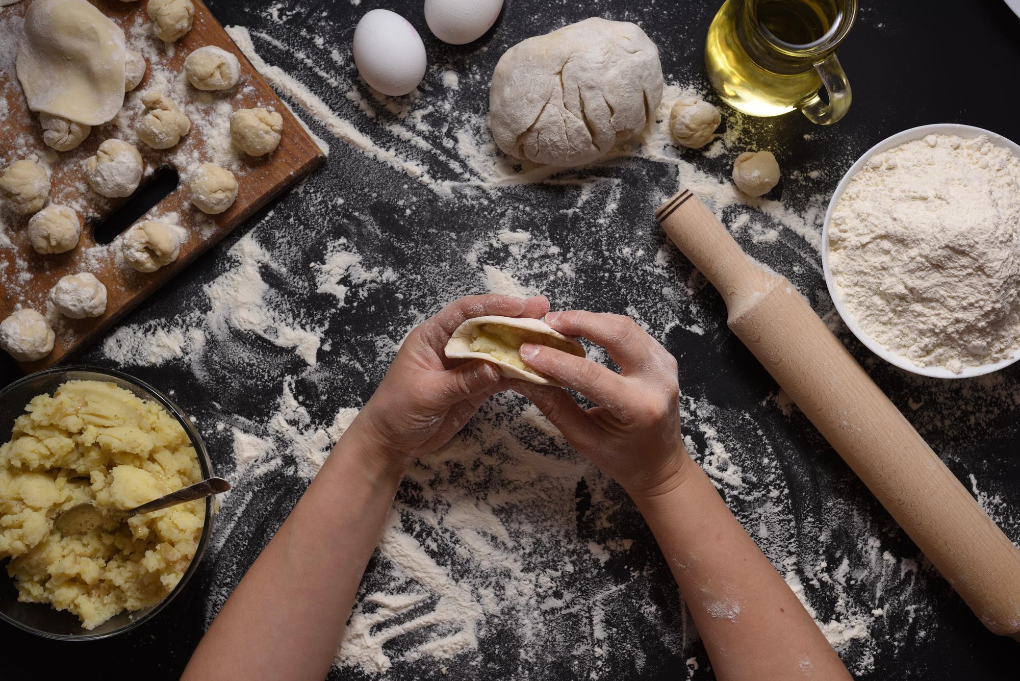 Hands shaping fresh pasta on floured board