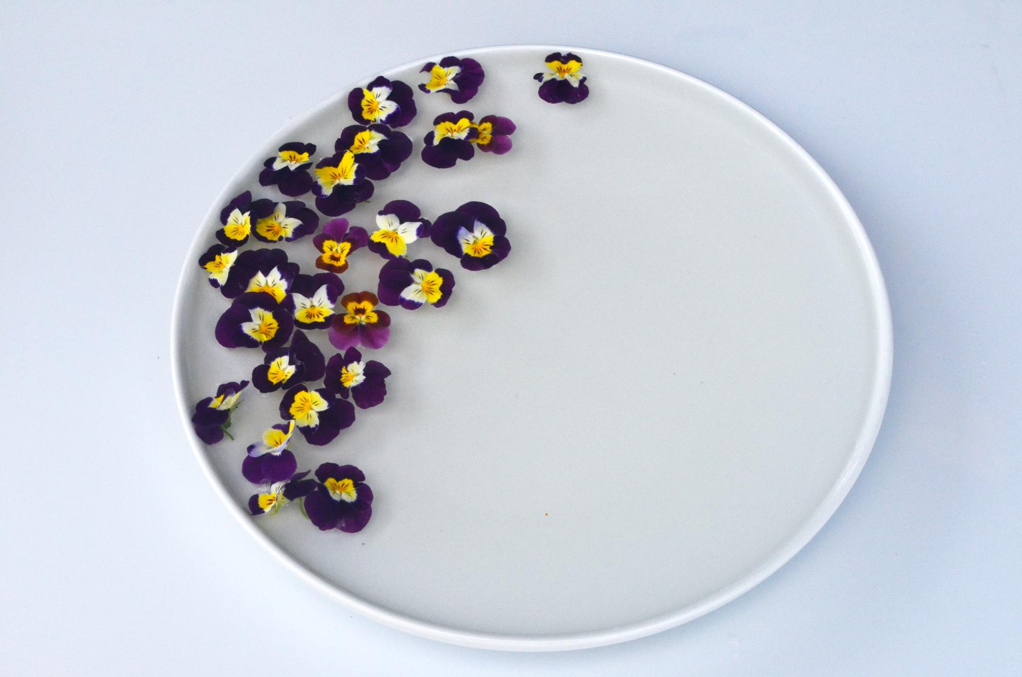 Minimal dessert with edible flowers on ceramic plate